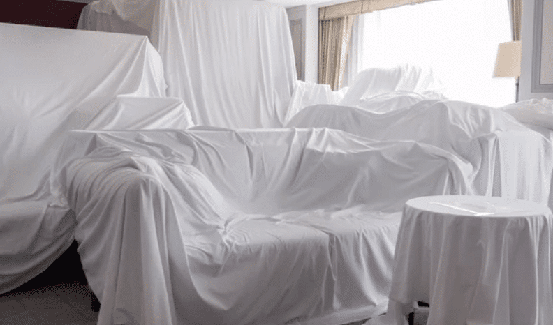 Immagine di mobili, tra cui un divano, coperti da lenzuoli bianchi