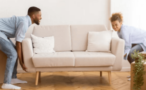 Una coppia che cerca di sollevare un divano a due posti