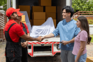 Due traslocatori che stringono la mano ad un ragazzo, accompagnato dalla sua fidanzata, davanti ad un furgone carico di scatoloni