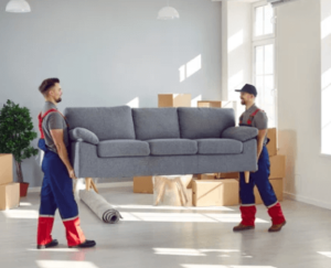 Due traslocatori che sollevano un divano a tre posti in tessuto grigio
