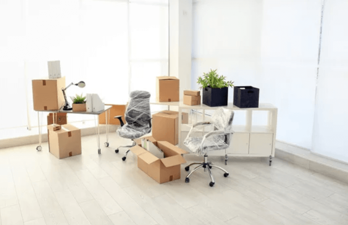 Una stanza di ufficio con alcuni mobili, due sedie imballate e molti scatoloni pronti per il trasloco ufficio